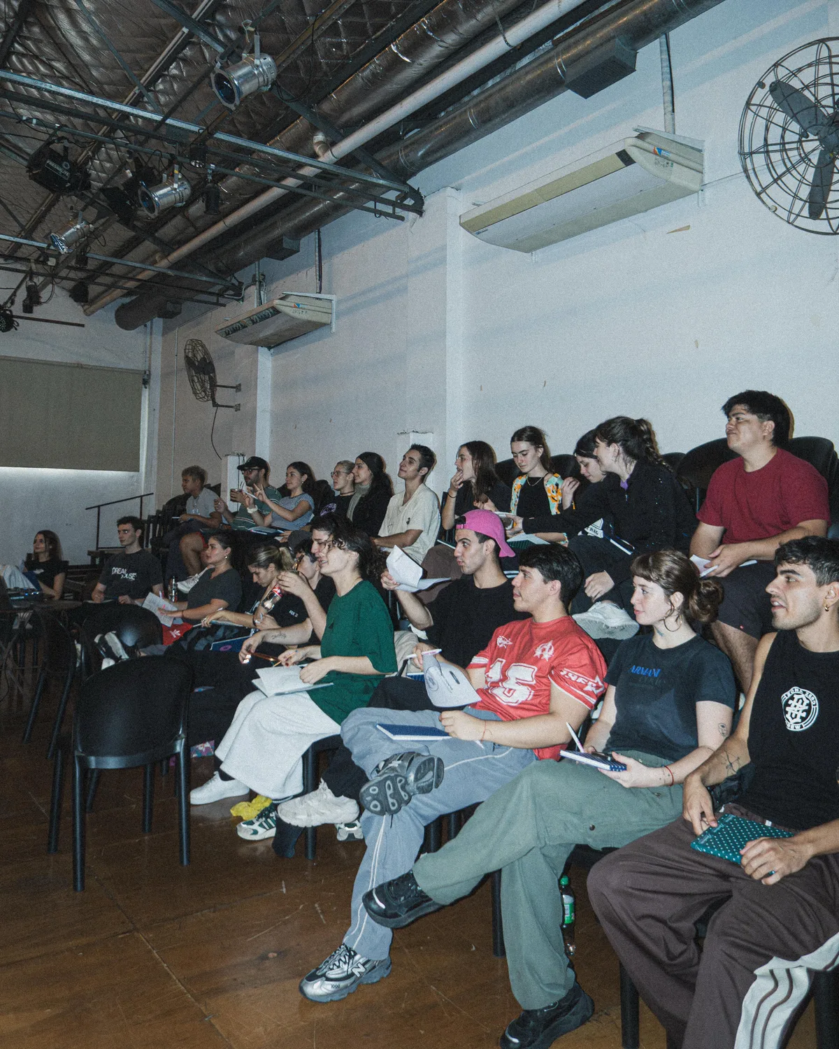 Audiencia de estudiantes tomando notas en sesión teórica