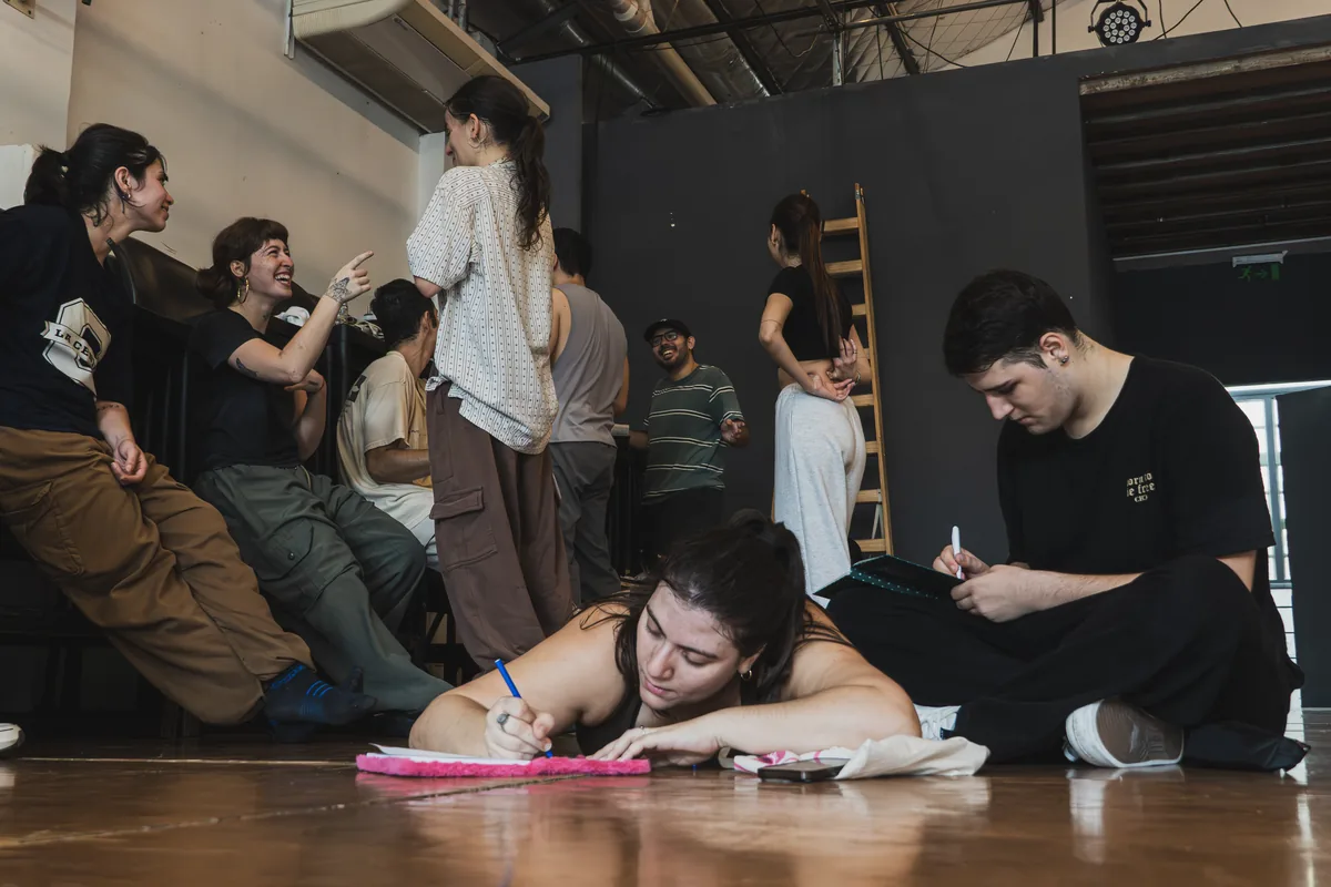 Estudiantes tomando apuntes en el piso del salón