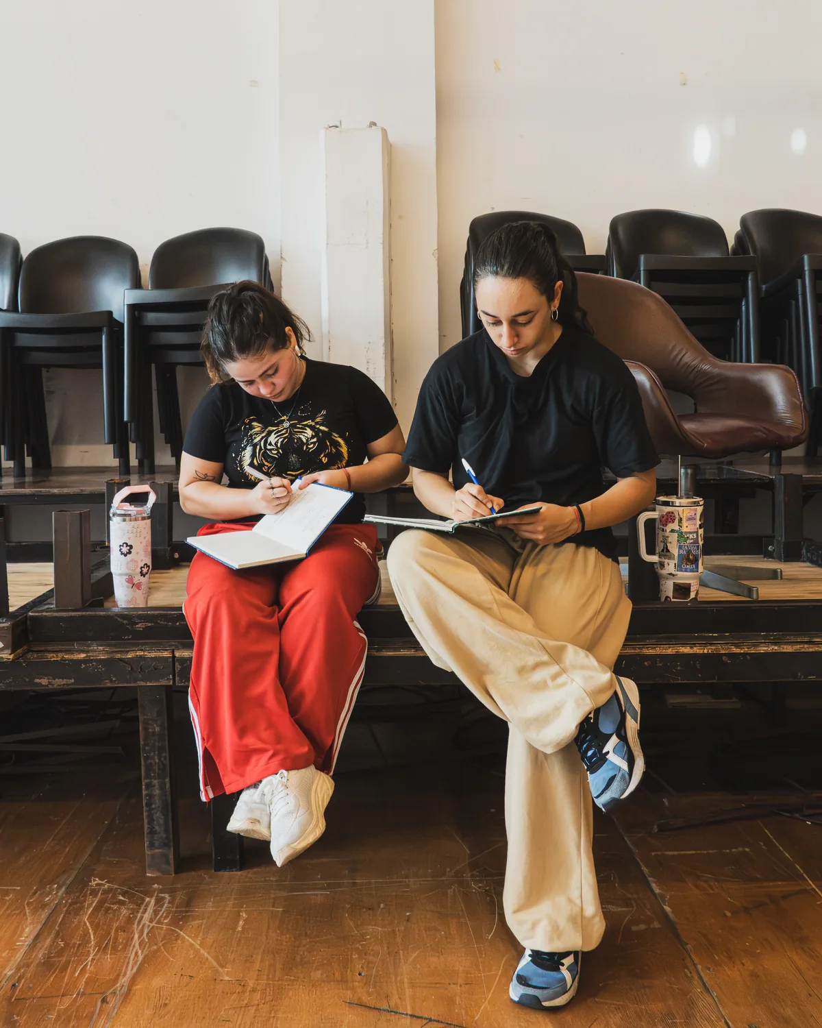 Dos alumnas tomando apuntes sentadas en un banco